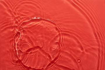 Wall Mural - Water red surface abstract background. Waves and ripples texture of cosmetic aqua moisturizer with bubbles.