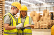 © chokniti - Warehouse worker logistic team wearing hard hat working in aisle between tall racks with packed goods warehouse for industry business of import, export delivery to global market, shipping management
