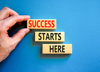 Wall Mural - Success starts here symbol. Concept word Success starts here on beautiful wooden block. Businessman hand. Beautiful blue background. Business motivational success starts here concept. Copy space.