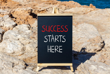 Wall Mural - Success starts here symbol. Concept word Success starts here on beautiful black blackboard. Beautiful stone beach sea blue background. Business motivational success starts here concept. Copy space