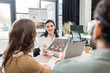 © LIGHTFIELD STUDIOS - cheerful team lead taking charts and discussing startup project with team in coworking space
