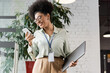 © LIGHTFIELD STUDIOS - positive african american businesswoman in glasses holding laptop and using smartphone in office