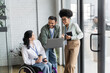 © LIGHTFIELD STUDIOS - happy disabled woman on wheelchair looking at indian man with laptop, diverse business people