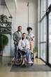 © LIGHTFIELD STUDIOS - group shot of diverse and inclusive business people looking at camera, wheelchair user in office