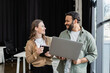 © LIGHTFIELD STUDIOS - happy indian businessman with laptop explaining task to female coworker with notebook, mentorship
