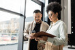 © LIGHTFIELD STUDIOS - african american woman showing startup project in folder to asian businessman in coworking
