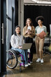 © LIGHTFIELD STUDIOS - three interracial businesswomen, happy disabled woman in wheelchair working with female team