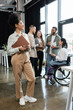 © LIGHTFIELD STUDIOS - pleased african american woman holding folder and standing near interracial team in coworking
