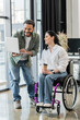 © LIGHTFIELD STUDIOS - cheerful indian businessman showing startup project on laptop to disabled woman in wheelchair