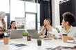 © LIGHTFIELD STUDIOS - joyful multiethnic business people discussing project near devices and sharing ideas with team lead