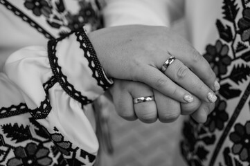 Wall Mural - black and white classic photo, close-up view of a young couple holding hands in embroidered traditional Ukrainian clothes