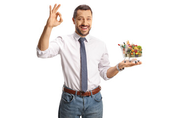 Wall Mural - Businessman holding a small shopping cart with food on his palm and gesturing ok sign