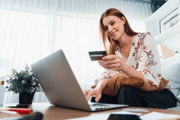 Young happy woman buy product by online shopping at home while ordering items from the internet with credit card online payment system protected by utmost cyber security from online store platform