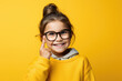 A young girl wearing glasses and a yellow sweater. Perfect for educational or back-to-school concepts.