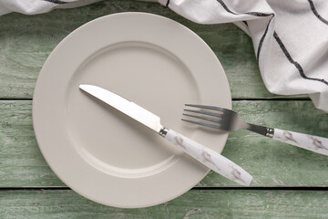 Wall Mural - Silver knife with fork, plate and kitchen towel on green wooden background