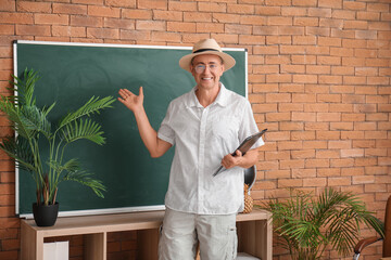 Sticker - Male teacher with clipboard conducting geography in classroom