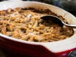 Traditional Swedish dish, Jansson's Frestelse, a casserole with potatoes, onion, anjovis and heavy cream, typically served at Christmas, here in a red pan with a spoon.