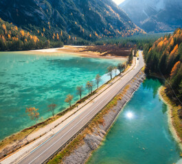 Poster - Aerial view of road, azure lakes, forest in alpine mountains in autumn sunny day. Dolomites, Italy. Travel. Top view of beautiful road, blue water, orange trees in fall. Landscape with highway. Nature
