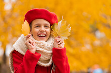 Happy Caucasian Girl In A Red Coat And Beret Walks In The Park In Autumn. 