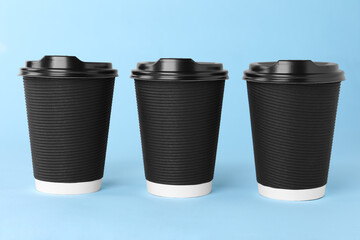 Poster - Paper cups with black lids on light blue background. Coffee to go