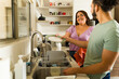 Cheerful couple doing the dishes after eating together sharing housework