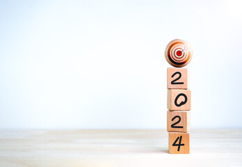 Poster - 2024 Happy New year banner. Big target icon on top of 2024 year number, handwriting text, on eco wooden cube blocks stacked on white background with copy space. Business growth and success concept.