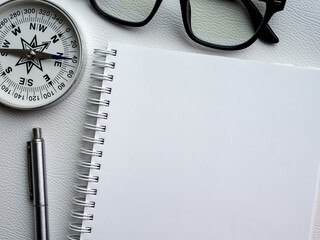 Wall Mural - Mockup space on new page on spiral notebook. White blank template on diary notepad with pen, compass and black glasses. Close-up paper for draw, sketch, note, to do list, creative and idea concepts.