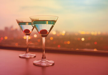 Wall Mural - Two cocktail glasses on bar and beautiful sunset  city night view 