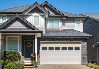 Real Estate Exterior Front House on a sunny day. Big luxury house with nicely landscaped front yard, driveway to garage