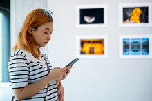 Visitor Woman Standing Takes Picture Art Gallery Collection In Front Framed Paintings Pictures On White Wall With Mobile Phone, People Watch At Photo Frame With Smartphone At Artwork Gallery Show