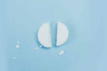 a white round tablet was cut into 2 equal parts. pill broken on half. pharmacy medicament concept.