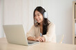 © Monster Ztudio - Young asian woman wearing headset while working on computer laptop at house. Work at home, Video conference, Video call, Student learning online class