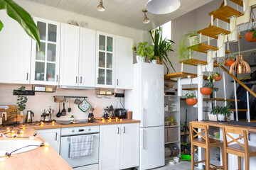 Wall Mural - The general plan of a light white modern rustic kitchen with a modular metal staircase decorated with potted plants. Interior of a house with homeplants