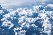 Aerial view of land, sea, soft white clouds from aeroplane window. Fluffy cotton cumulus cloud in blue sky