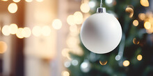 Close Up Of A White Mock Up Christmas Ornament Hanging On A Tree, Blurred Lights Background 