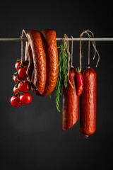 Wall Mural - Traditional smoked salami sausage with rosemary on a dark background