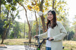 © MIND AND I - Happy woman riding bicycle at park.