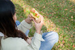 © MIND AND I - Young woman eating meal at park.