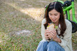 © MIND AND I - Young woman eating meal at park.