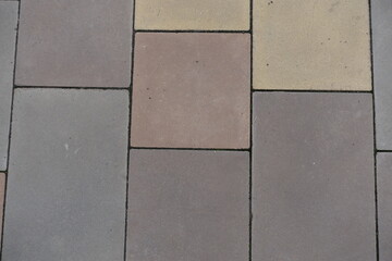 Wall Mural - Close up of pavement made of pink, yellow, brown and grey concrete blocks