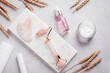 Facial roller, gua sha, serum and moisturizing cream on marble background