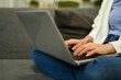 © Prathankarnpap - Cropped shot of young woman sitting on sofa and using laptop browsing internet, remote work or stying online