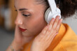 © Studio Marmellata - Crop portrait of young pensive female with stylish hair looking down and touching wireless headphones while listening to music