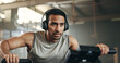 © Felix/peopleimages.com - Asian man, headphones and cycling at gym on machine and listening to music in sports workout or exercise. Serious male person or athlete training on bicycle machine or equipment for healthy cardio