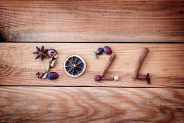 Wall Mural - 2024 written with Christmas spices and dried fruits on wooden background, new year greeting card