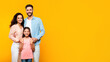 © Prostock-studio - Happy loving family. European mother and father posing with their daughter on yellow background, panorama, free space
