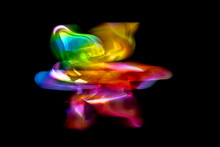 A Front View Of A Regular Toy Pinwheel Windmills With Six Differently Psychedelic Colored Vanes Rotating On A Stick On A Black Screen Background, Slow Shutter Speed Motion Blur