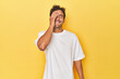 © Asier - Young Latino man posing on yellow background laughing happy, carefree, natural emotion.
