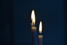 Closeup Shot Of Two Lit Candles Slowly Burning In A Dark Room
