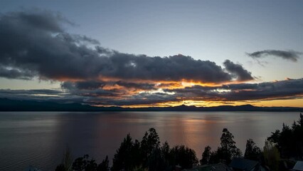 Wall Mural - landscape timelapse scene of cloudy sky moving over lake with trees at sunset.